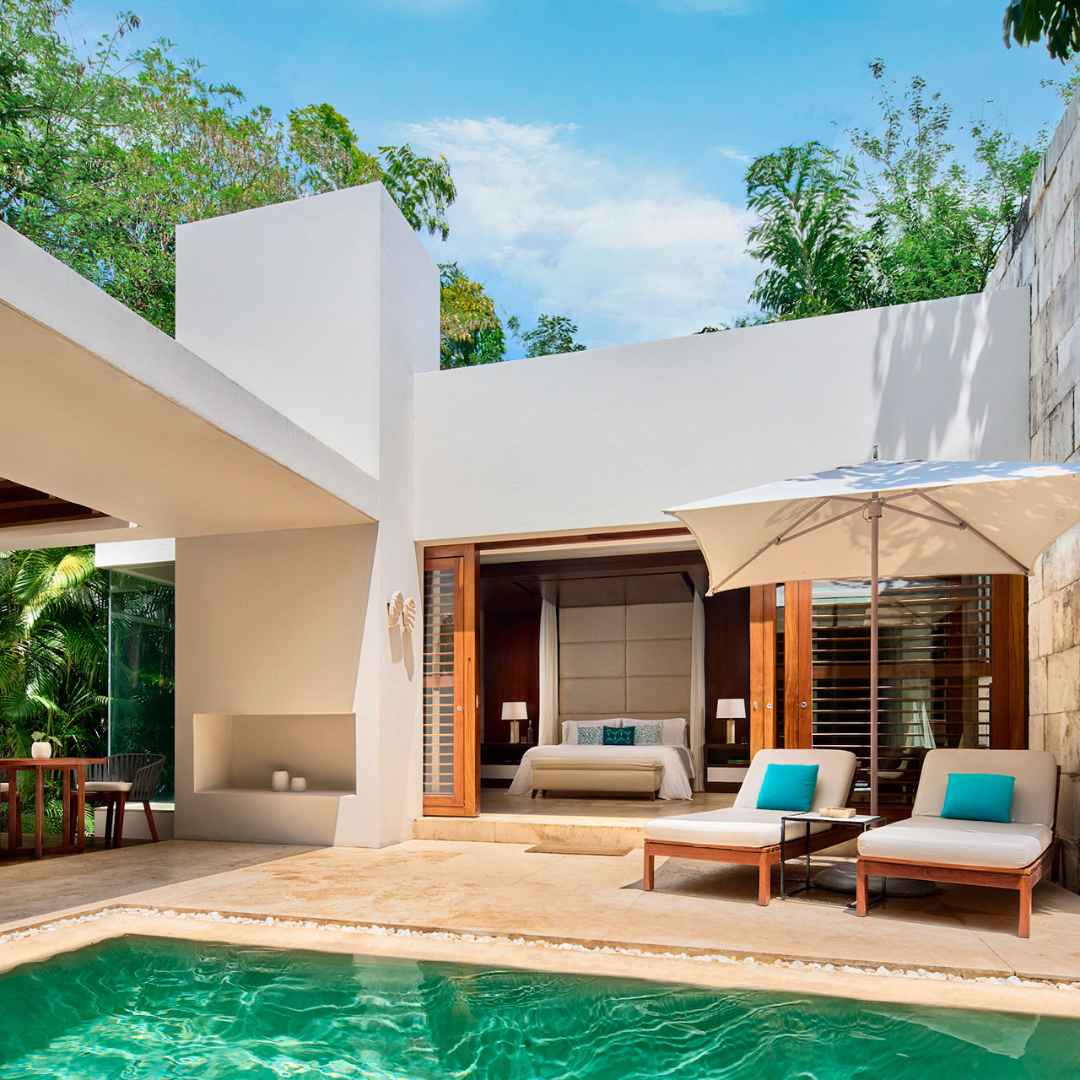 A photograph showcasing a luxurious villa at Chablé Spa & Resort. The contemporary architecture and expansive windows seamlessly integrate with lush green surroundings.