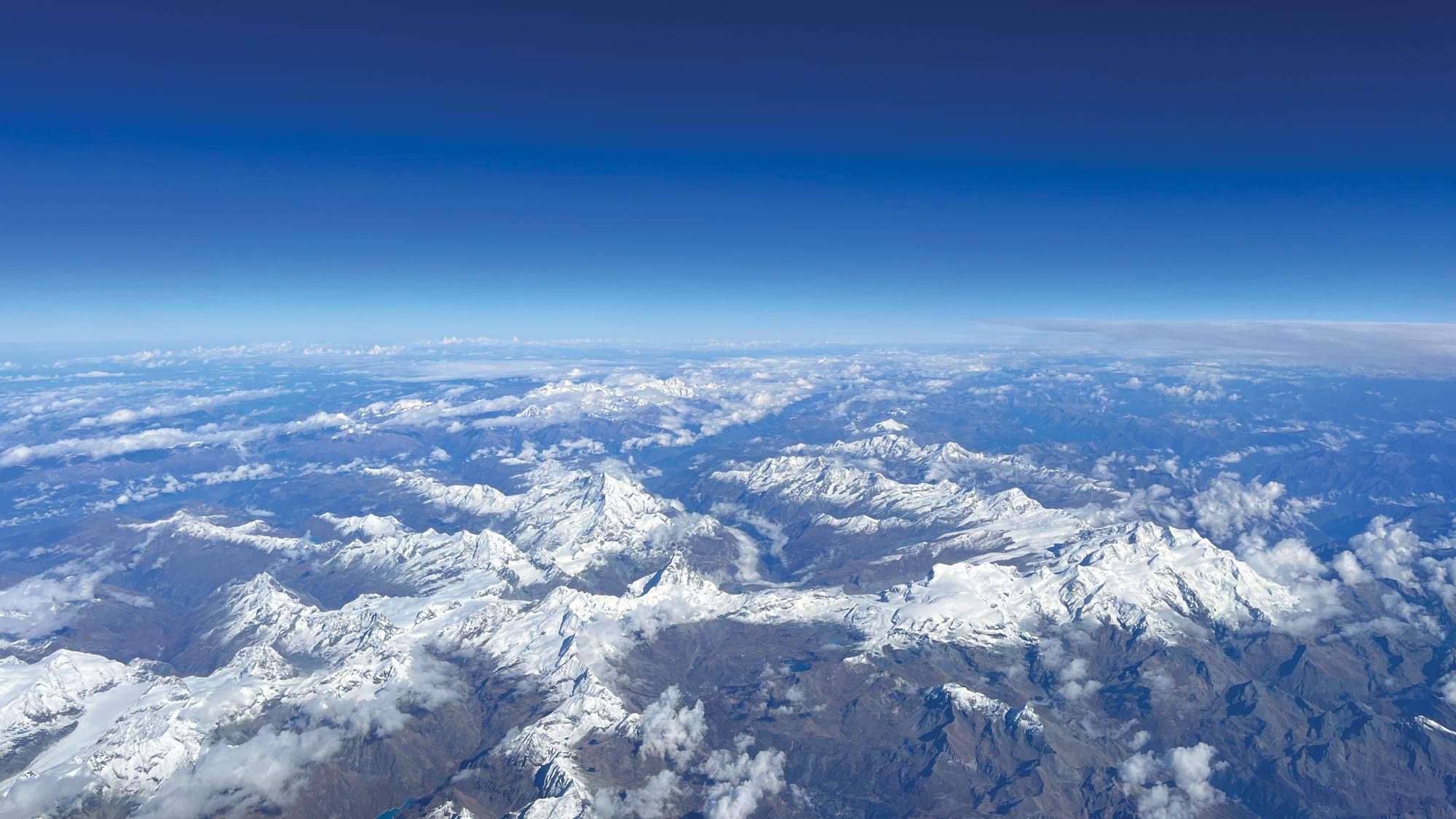 An expansive aerial view of Greenland, showcasing its vast icy landscapes and rugged mountains.