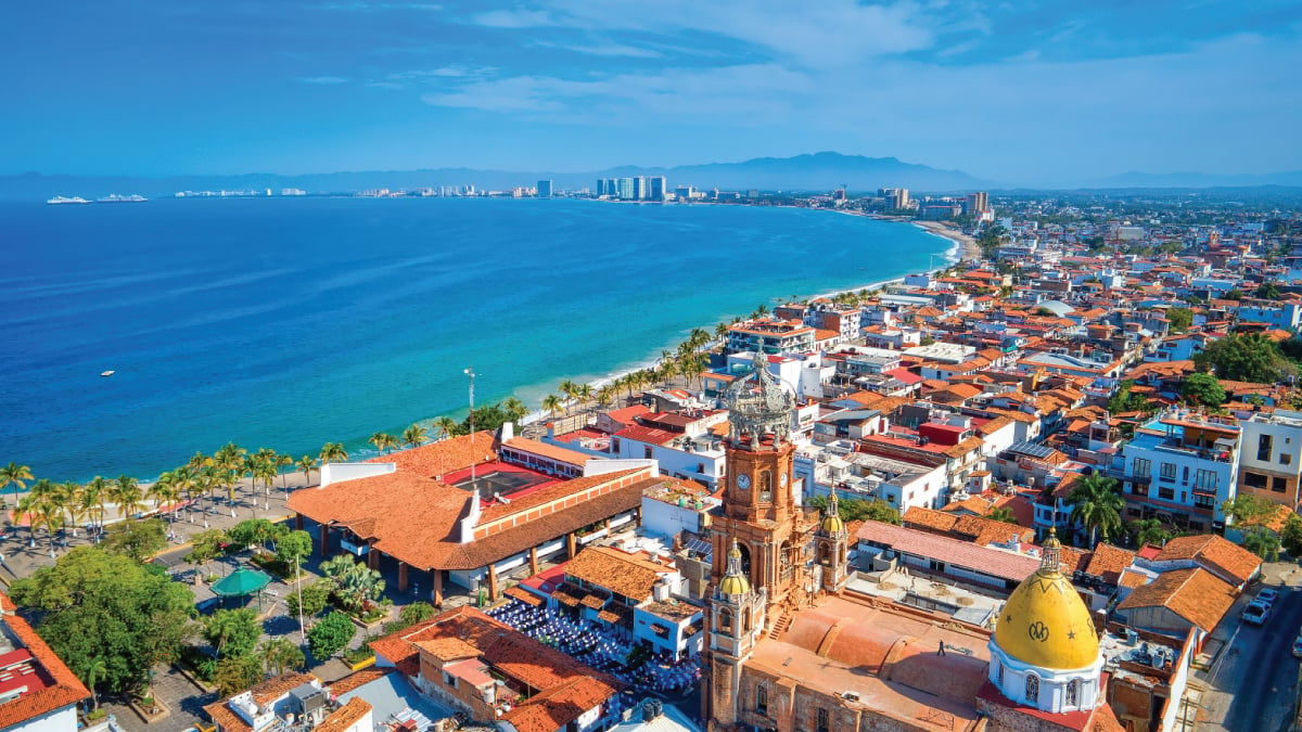 A breathtaking aerial vista of Puerto Vallarta, Mexico, showcasing its sprawling cityscape against the backdrop of the Pacific Ocean. An enticing destination for self-flying pilots, offering a blend of urban charm, coastal allure, and adventure in the heart of Mexico.