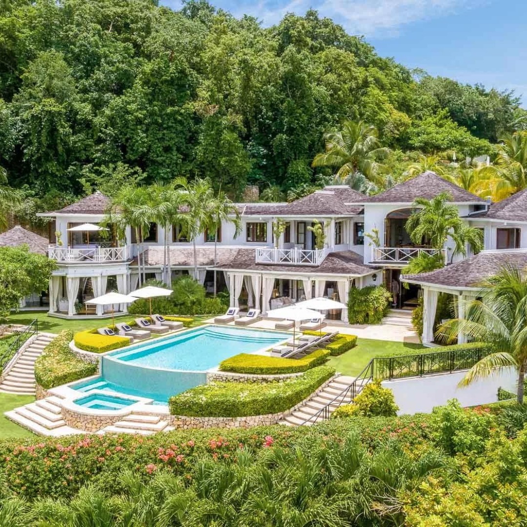 An enchanting aerial view of Round Hill Hotel in Montego Bay, Jamaica. The hotel's elegant facade and inviting pool are embraced by lush greenery, creating a harmonious blend of Caribbean luxury and natural beauty. A captivating retreat nestled in the heart of Jamaica's tropical paradise.
