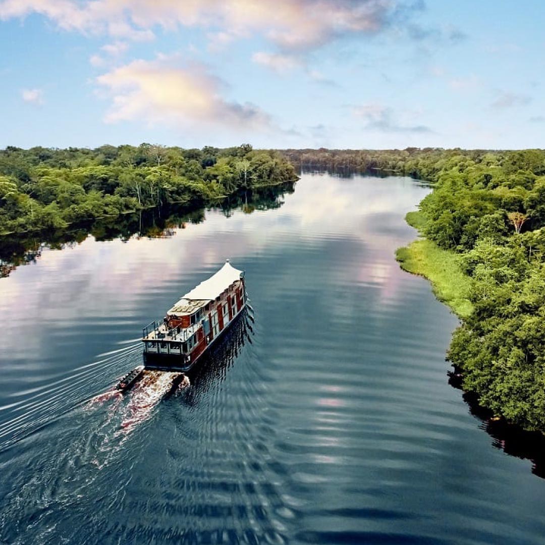A captivating view of the M/V Amazon Aria gracefully cruising along the Amazon River in Peru, surrounded by lush rainforest and tranquil waters. A thrilling destination for self-flying pilots exploring South America