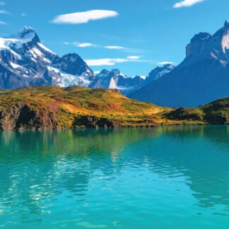 An enchanting aerial view of a serene lake nestled within the pristine wilderness of Chilean Patagonia, surrounded by towering mountains and lush forests. A captivating destination for self-flying pilots exploring South America