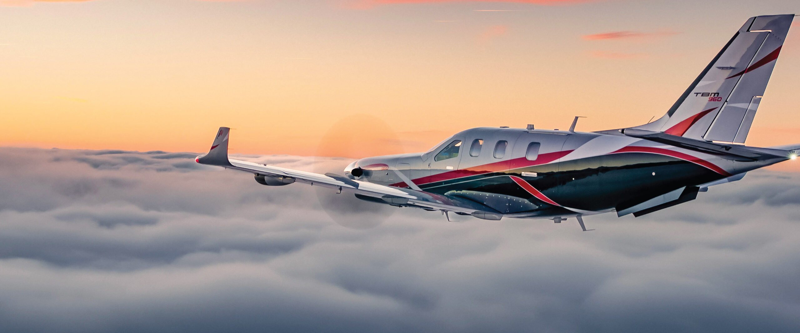A stunning image of a TBM aircraft flying at sunset over picturesque European landscapes. Tailored for self-flying pilots