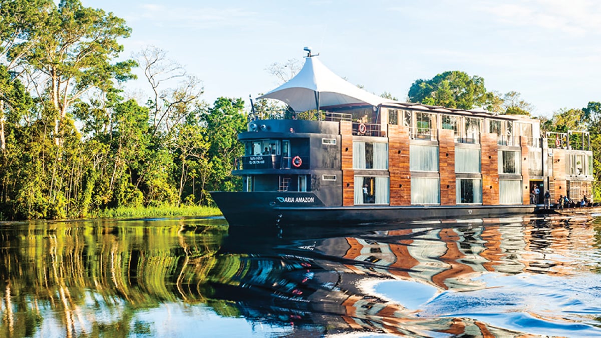 A captivating view of the M/V Amazon Aria gracefully cruising along the Amazon River in Peru, surrounded by lush rainforest and tranquil waters. A thrilling destination for self-flying pilots exploring South America