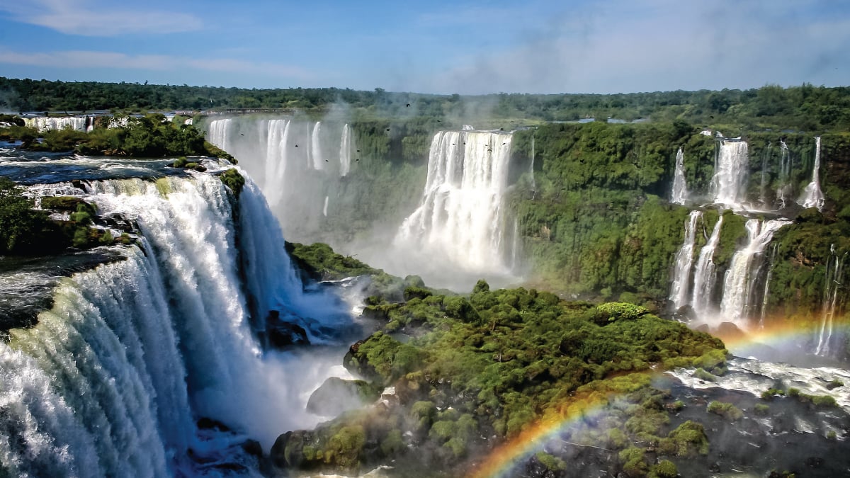 An awe-inspiring aerial view of Iguazu Falls in Argentina, showcasing the majestic waterfalls amidst lush tropical foliage. A captivating destination for self-flying pilots exploring South America.