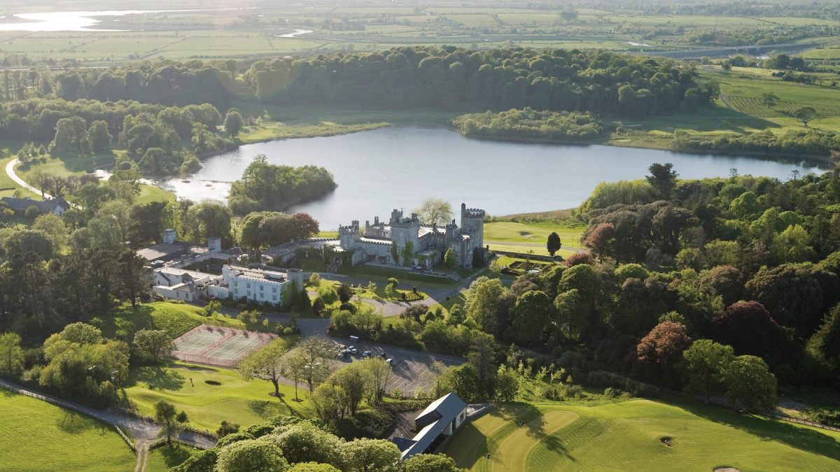 A mesmerizing aerial view of Dromoland Castle in Shannon, Ireland, nestled amidst lush greenery and rolling hills. Tailored for self-flying pilots planning a European adventure