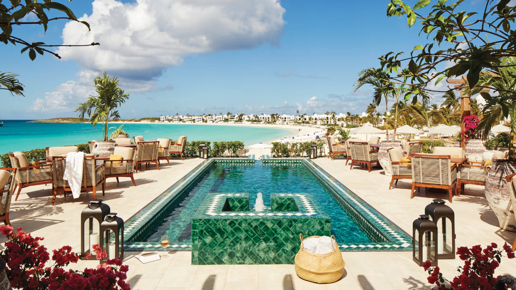 A tranquil scene of the pool at Belmond Cap Juluca in The Valley, Anguilla, surrounded by lush greenery and overlooking the azure Caribbean Sea. Tailored for self-flying pilots