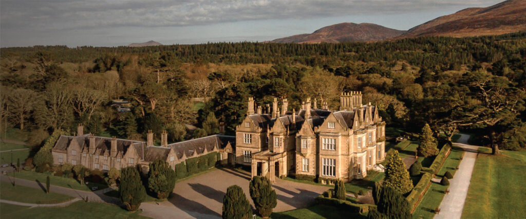 A mesmerizing aerial view of Muckross House in Kerry, Ireland, nestled amidst lush greenery and rolling hills. Tailored for self-flying pilots planning a European adventure