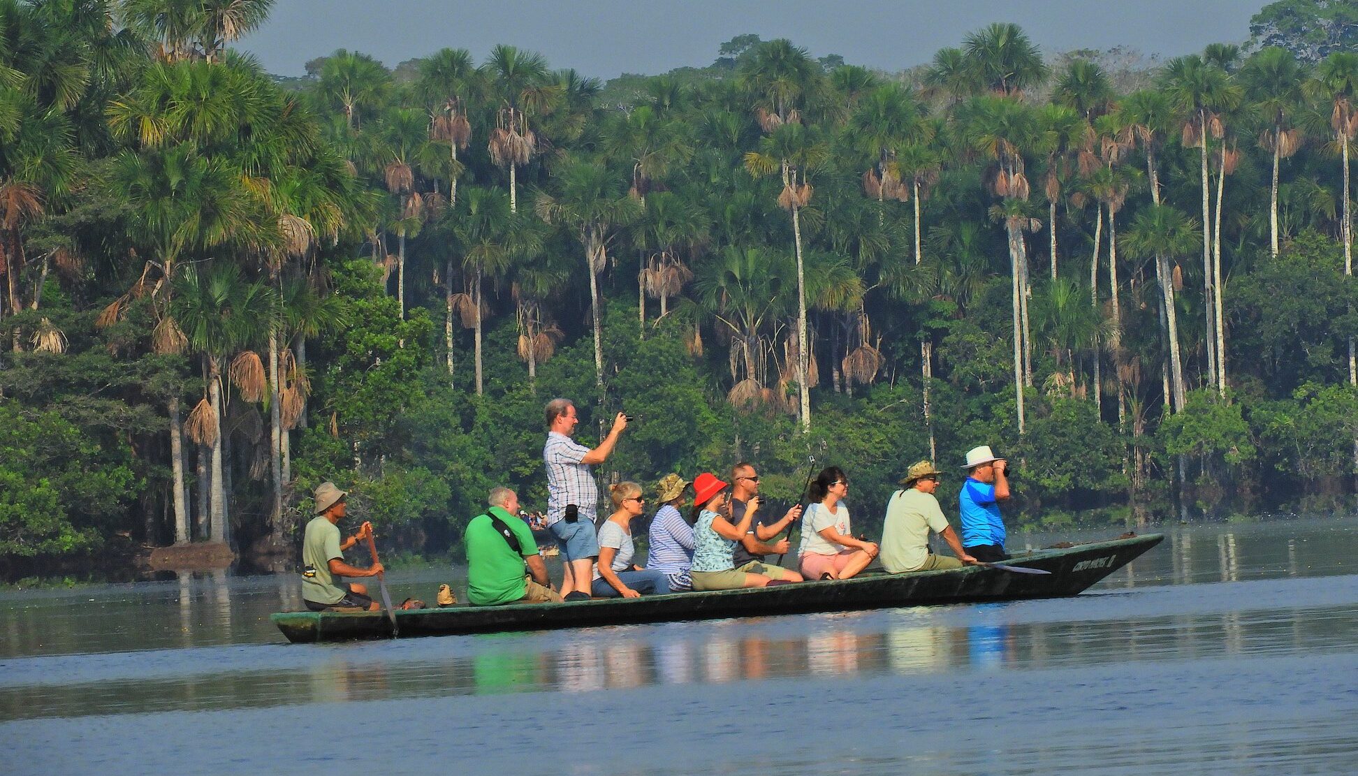 A group of travelers gliding along the Amazon River in a traditional wooden gondola in Peru, immersing themselves in the pristine natural beauty of the rainforest.