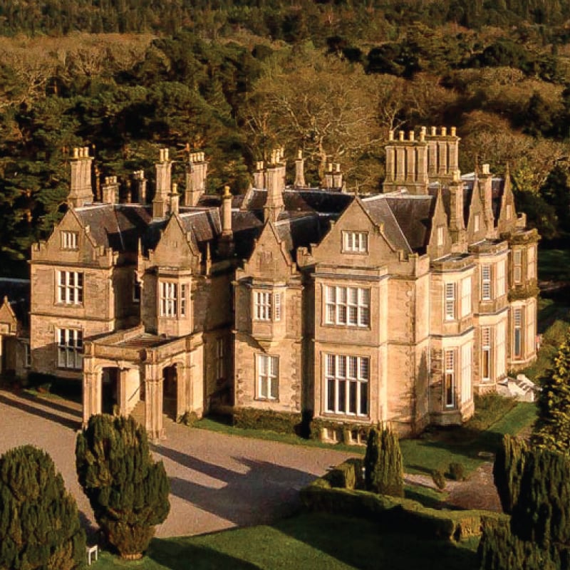 A mesmerizing aerial view of Muckross House in Kerry, Ireland, nestled amidst lush greenery and rolling hills. Tailored for self-flying pilots planning a European adventure