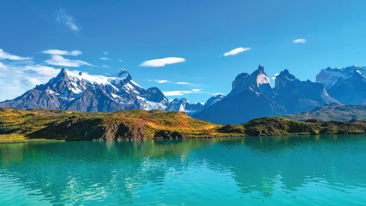 An enchanting aerial view of a serene lake nestled within the pristine wilderness of Chilean Patagonia, surrounded by towering mountains and lush forests. A captivating destination for self-flying pilots exploring South America
